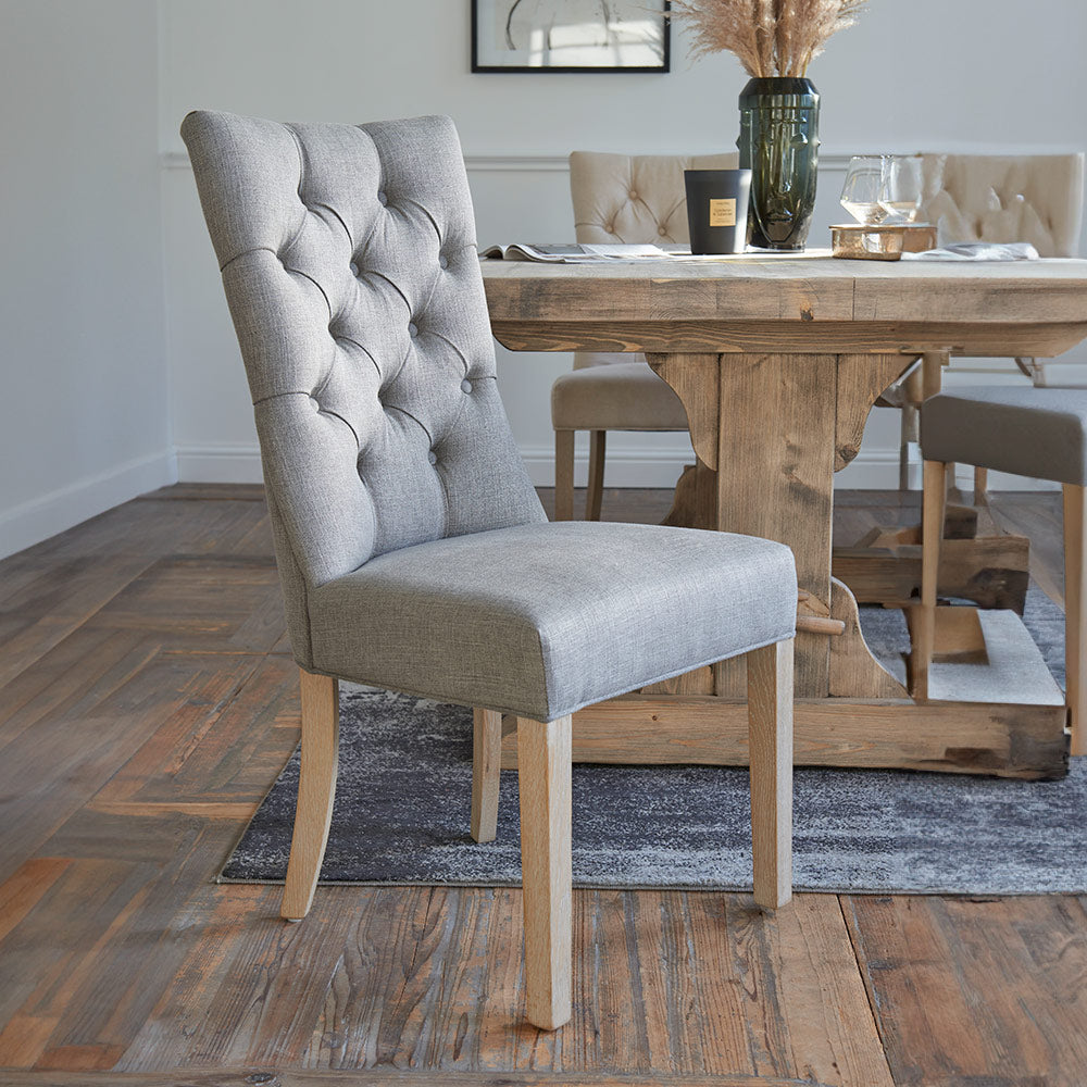 Upholstered dining chair in grey fabric with studded back and wooden legs