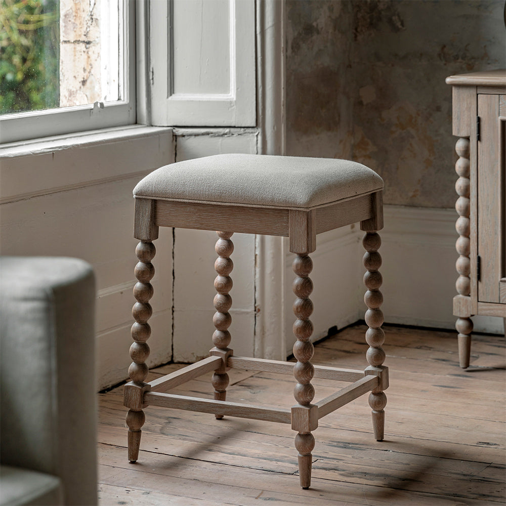 Oak small barstool in lime wash finish, handcrafted bobbing detailed legs and upholstered neutral fabric seat