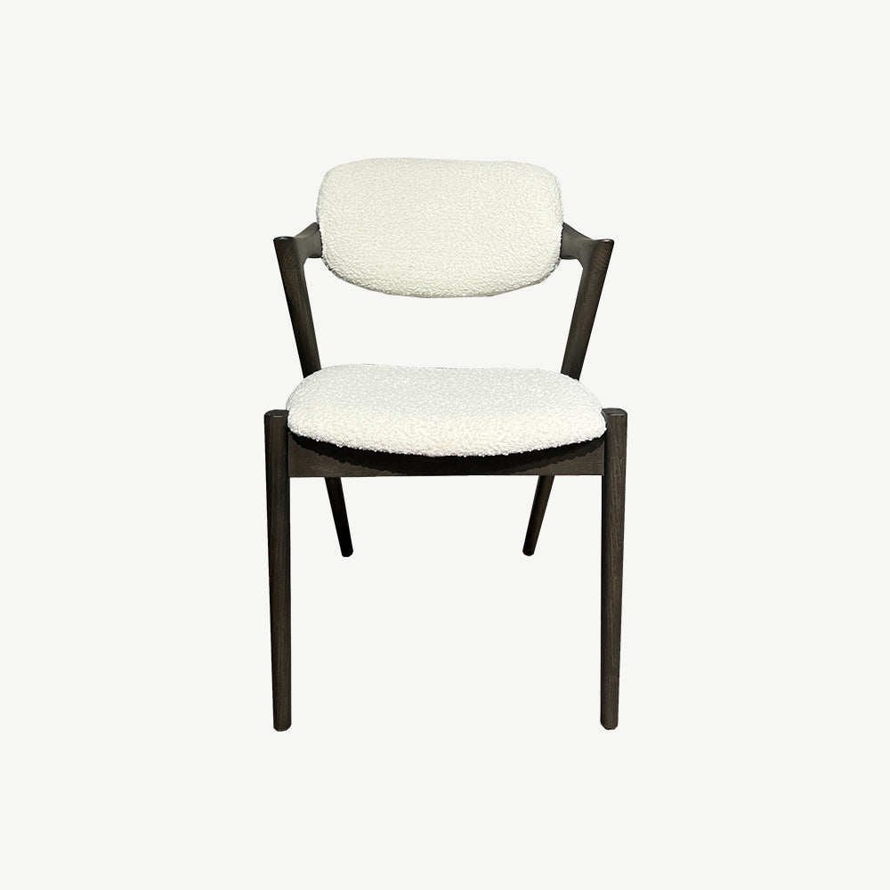 Dining chair featuring upholstered padded seat and back cushions. Neutral light colour of the upholstery complements the dark wood frame and legs