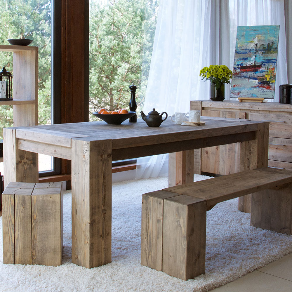 A rustic, rectangular wooden dining table with thick, block-style legs and a natural, unfinished look.