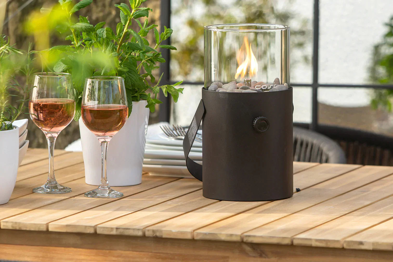 A tabletop lantern and two wine glasses on an outdoor table