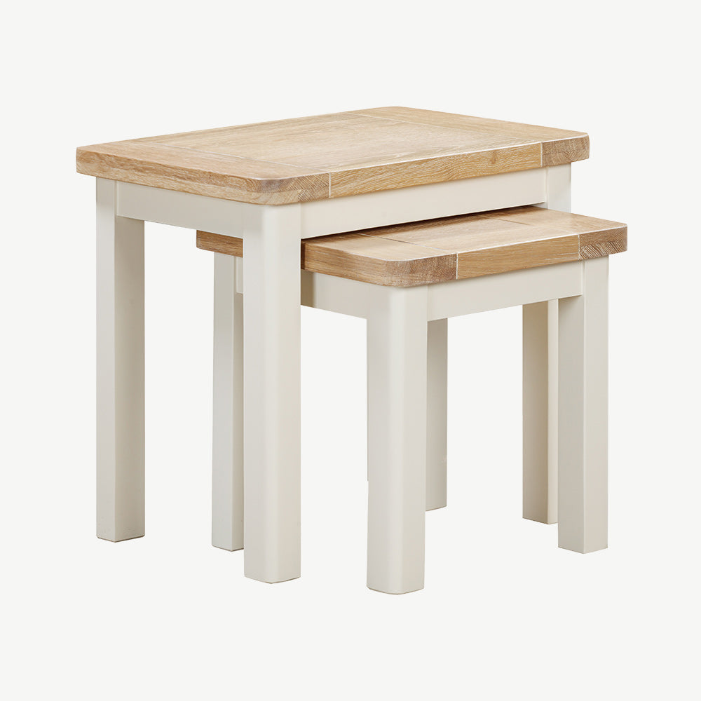 Painted off-white nest of tables with natural wood top, smaller table partially concealed under larger table
