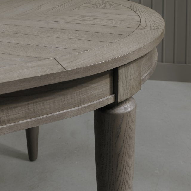 Oval shaped extending wooden dining table with saw-cut ash chevron pattern in silver grey finish