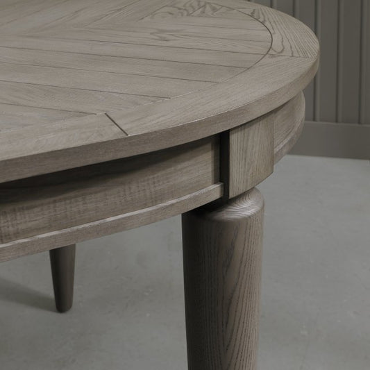 Oval shaped extending wooden dining table with saw-cut ash chevron pattern in silver grey finish