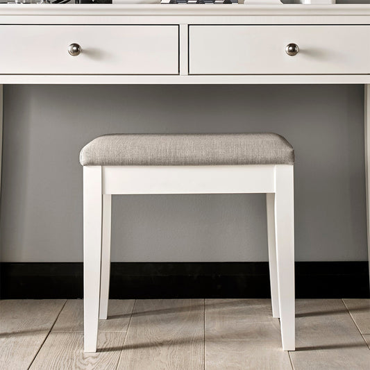 Bedroom stool in painted white upholstered with textured pebble grey fabric
