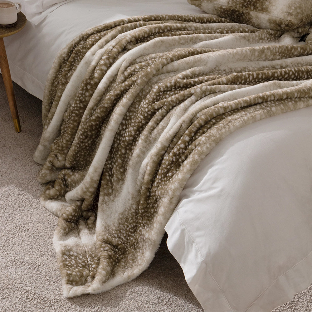 Brown textured blanket draped over a bed in a bedroom setting.