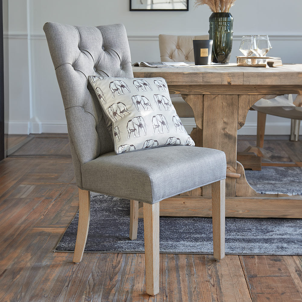 Upholstered dining chair in grey fabric with studded back and wooden legs