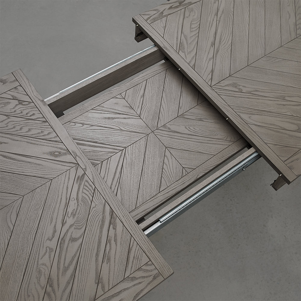 Oval shaped extending wooden dining table with saw-cut ash chevron pattern in silver grey finish