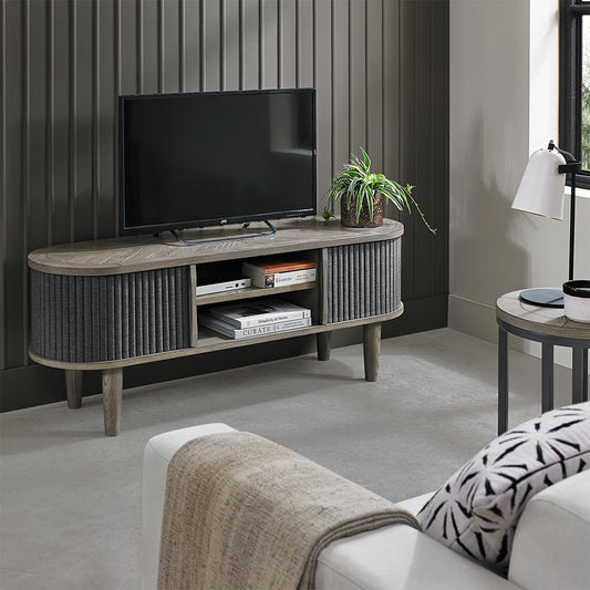 Wooden entertainment unit with saw-cut ash chevron pattern in silver grey finish and black powder coated metal base
