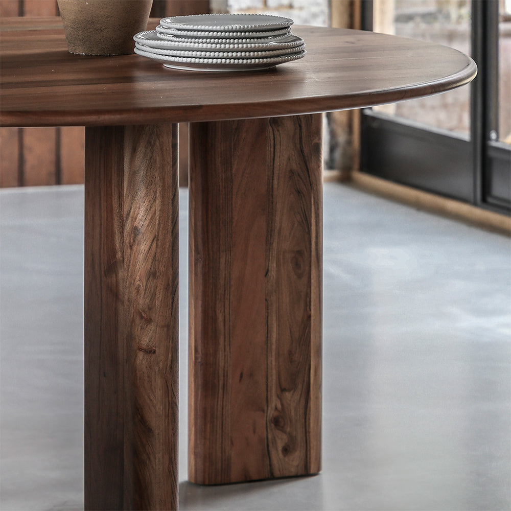 Acacia wood round dining table in natural finish with wide angled legs
