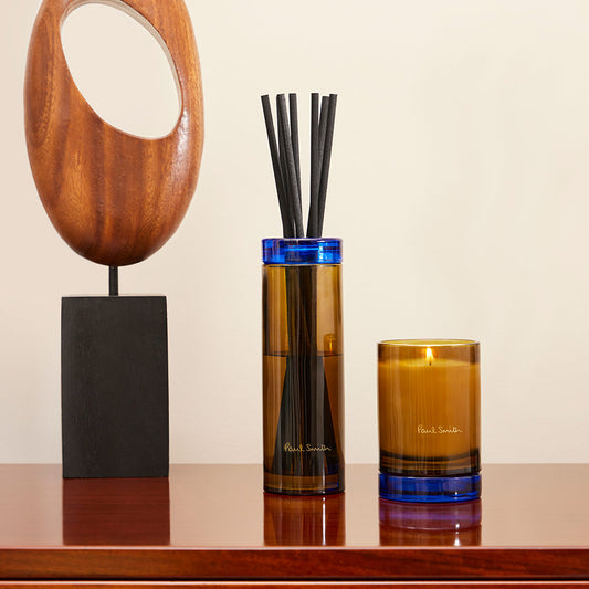 Paul Smith Daydreamer Scented Candle housed in tinted yellow glass vessel and contrasting collar that doubles as a coaster