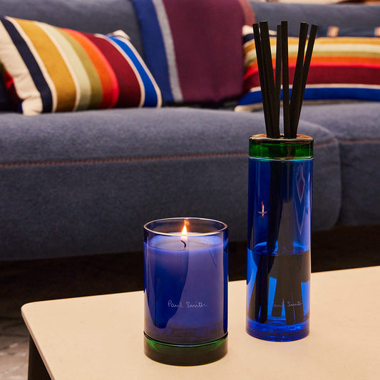 Paul Smith Early Bird Scented Candle housed in tinted blue glass vessel and contrasting collar that doubles as a coaster