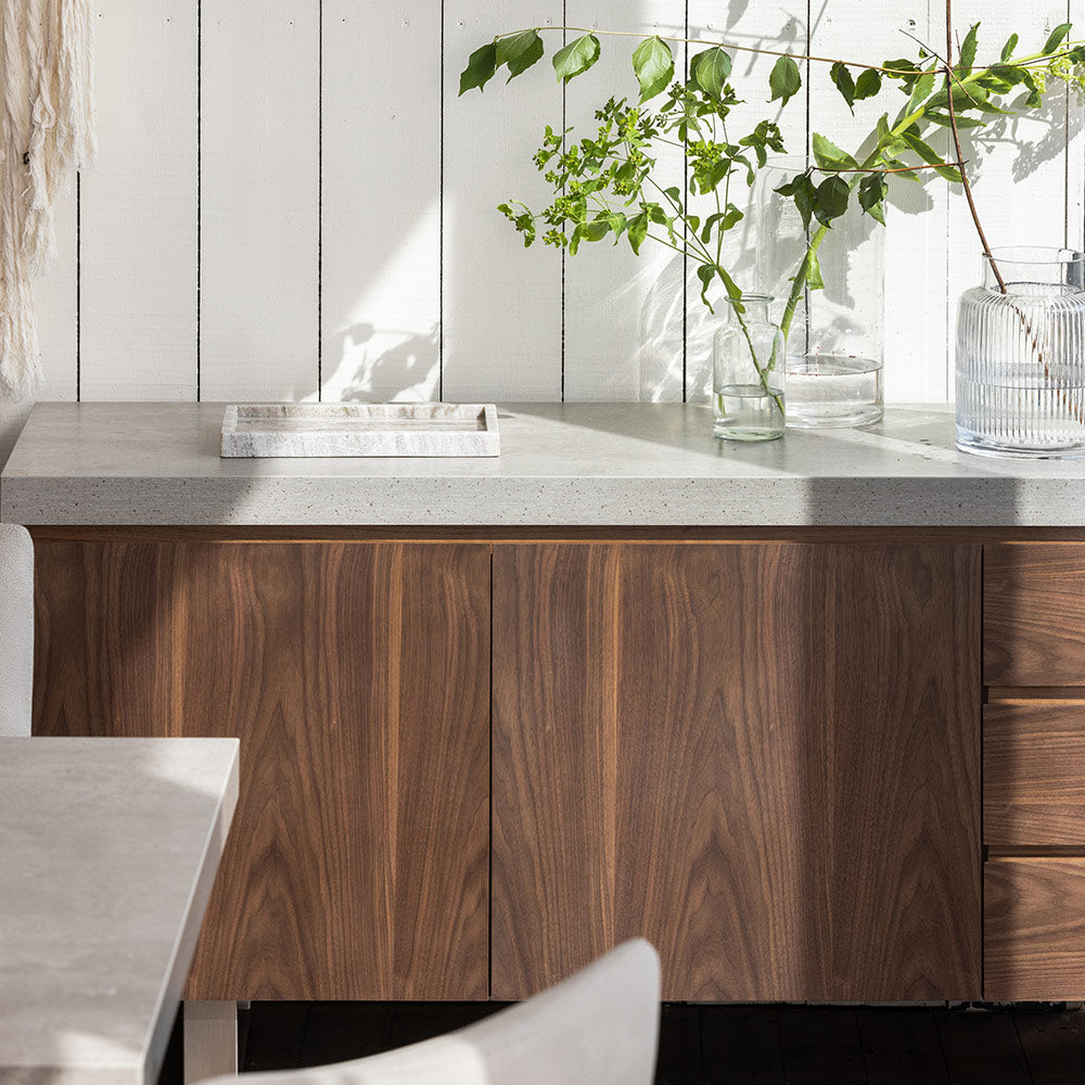 Walnut veneer wide sideboard with neutral grey toned top, double cupboard, three drawers and stainless steel legs