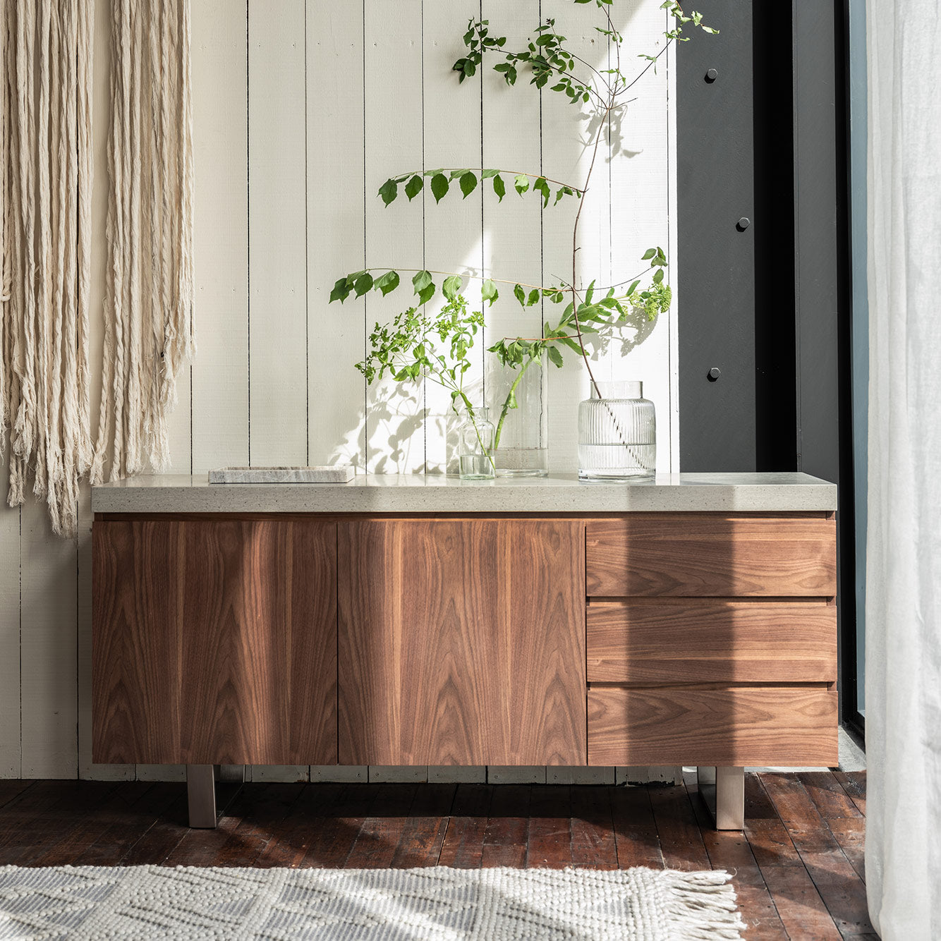 Walnut veneer wide sideboard with neutral grey toned top, double cupboard, three drawers and stainless steel legs
