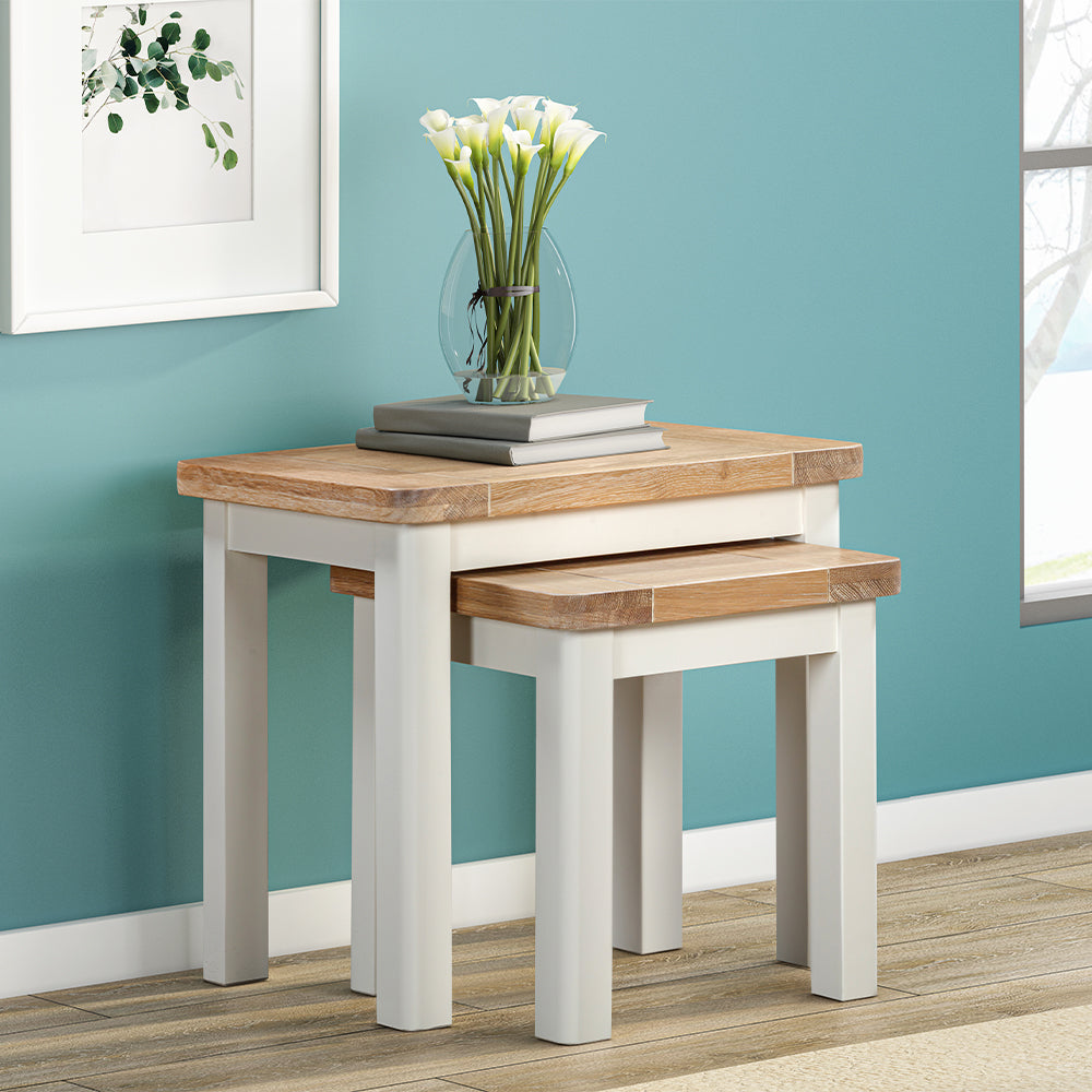 Painted off-white nest of tables with natural wood top, smaller table partially concealed under larger table
