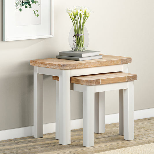 Painted off-white nest of tables with natural wood top, smaller table partially concealed under larger table
