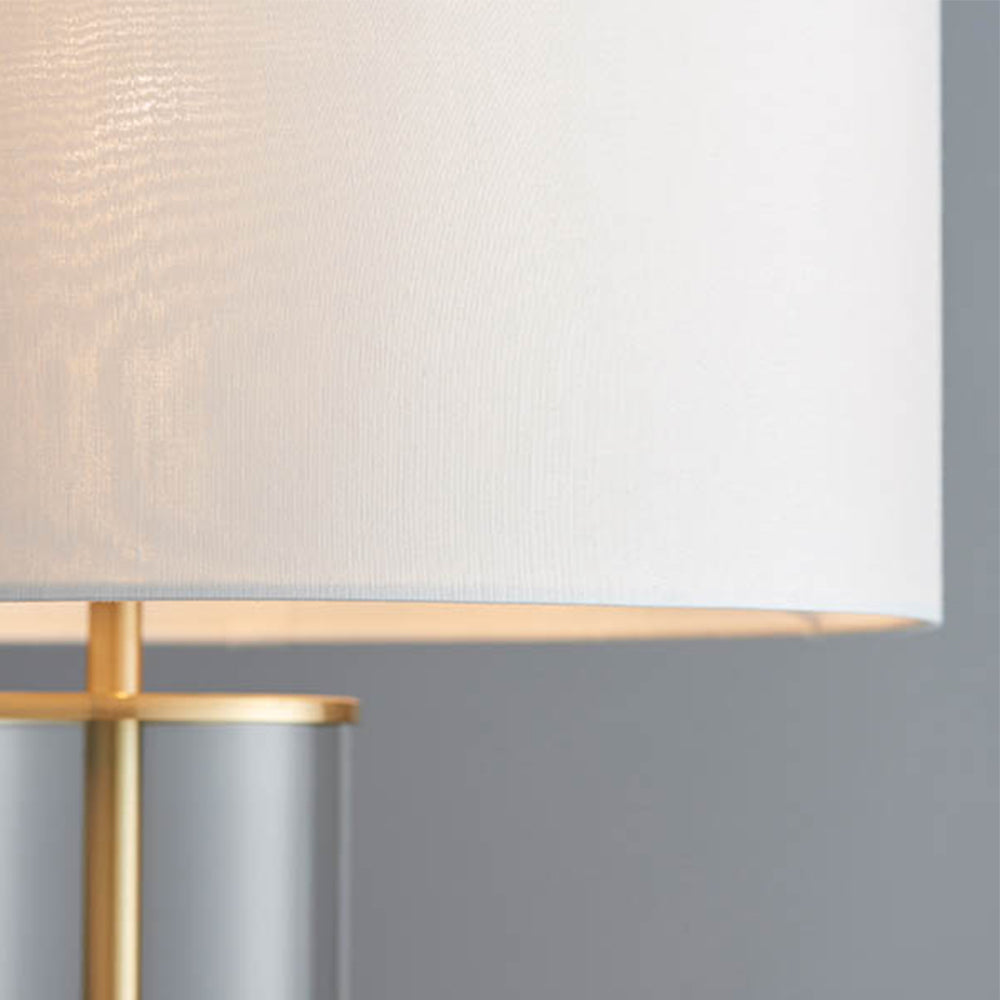 Simple  table light with a clear glass base, vintage white faux silk shade and a brushed gold effect finish