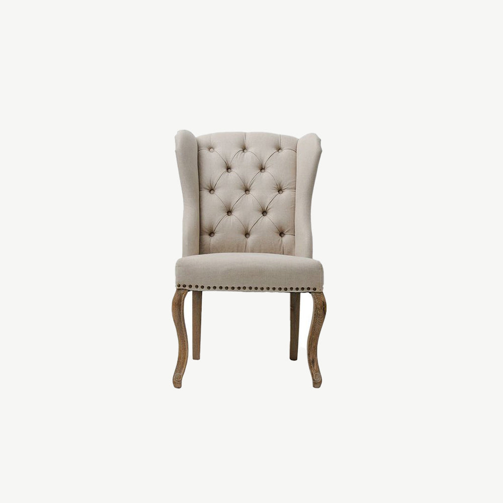 Button back dining chair with studded detailing in a neutral fabric and wooden legs