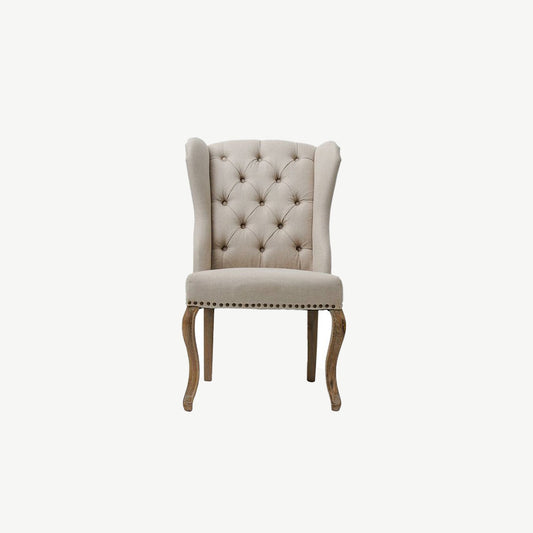 Button back dining chair with studded detailing in a neutral fabric and wooden legs